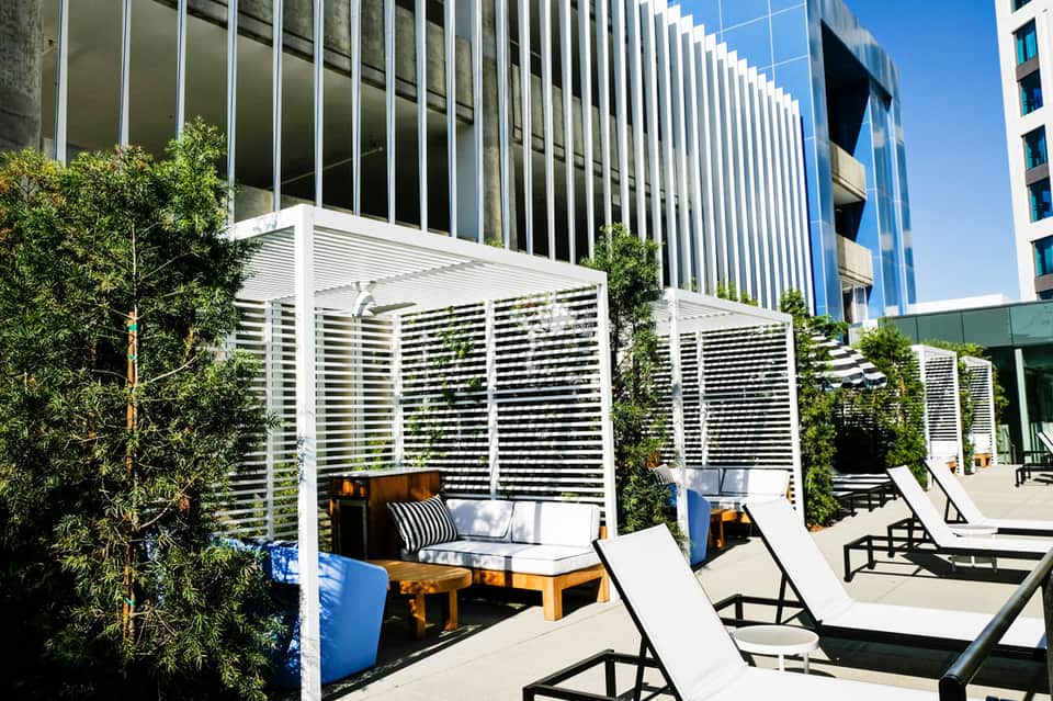 Modern rooftop lounge with white pergola, loungers, and city skyline views
