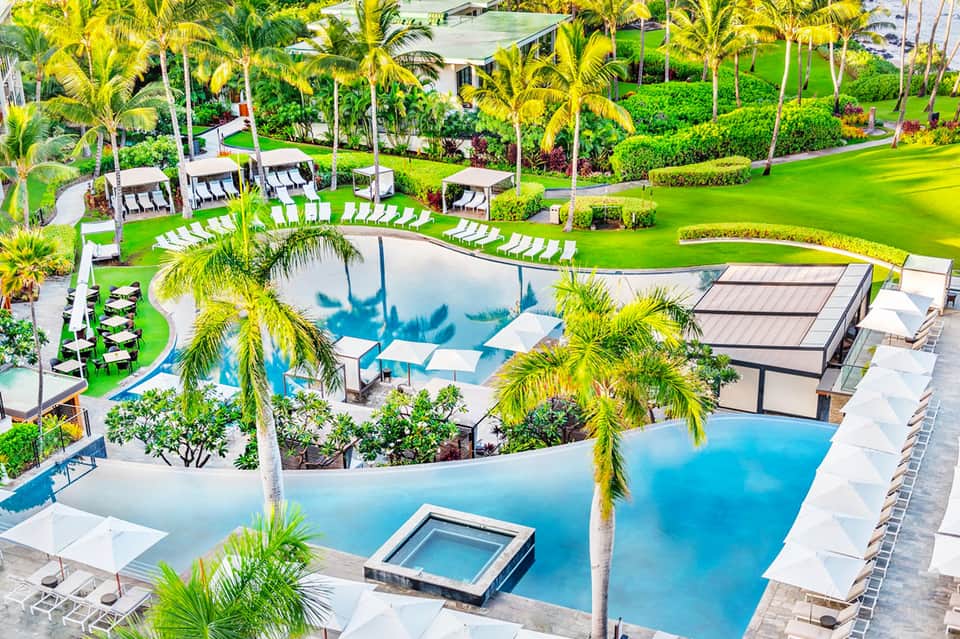 Aerial view of luxury resort pools with palm trees, cabanas, and manicured lawns
