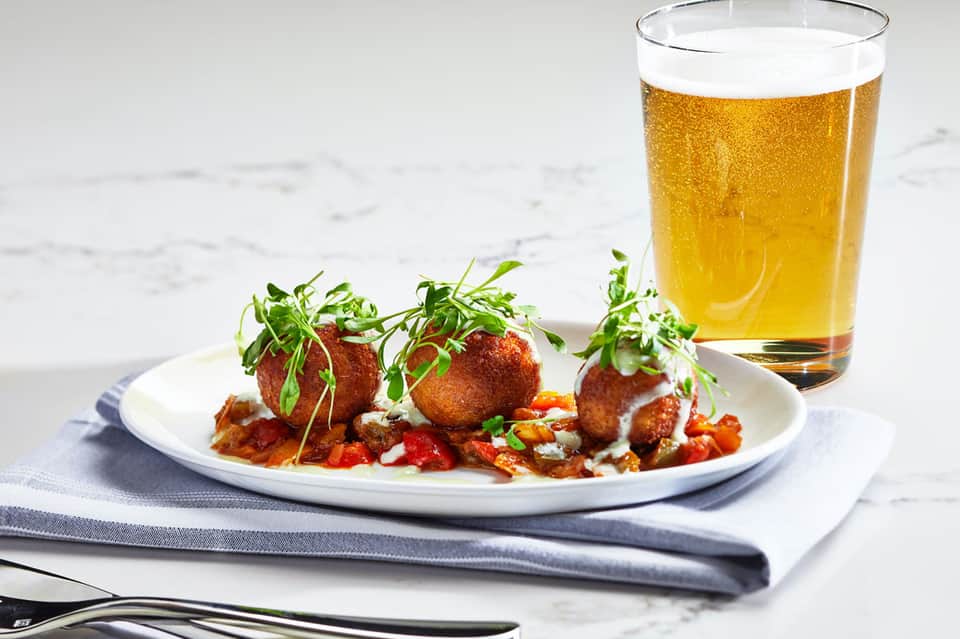 Fried appetizers with microgreens and beer on marble surface