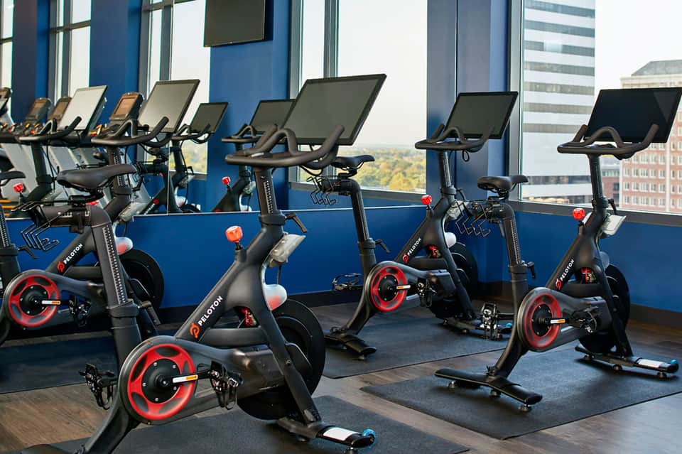 Indoor cycling studio with stationary bikes and floor-to-ceiling windows overlooking cityscape