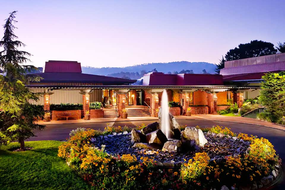 Modern resort building at dusk with illuminated brick facade and fountain