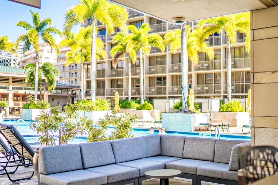 Hotel courtyard with palm trees, seating area, and pool views