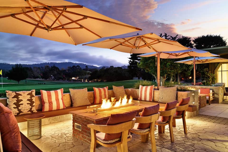 Outdoor patio at dusk with fire pit, lounge seating, umbrellas, and mountain views