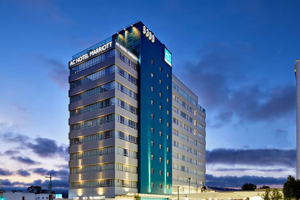 Modern AC Hotel Marriott building at dusk with illuminated facade and blue accents