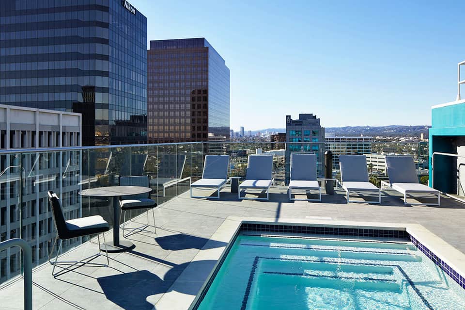 Rooftop pool deck with loungers and city skyline views from a high-rise hotel
