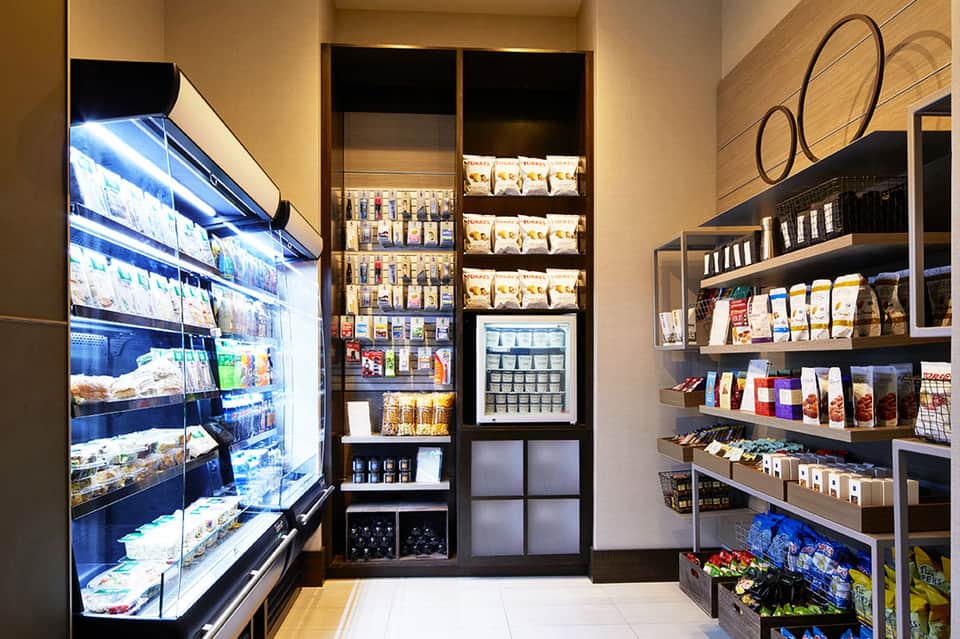 Modern convenience store interior with refrigerated cases, shelving units, and packaged snacks