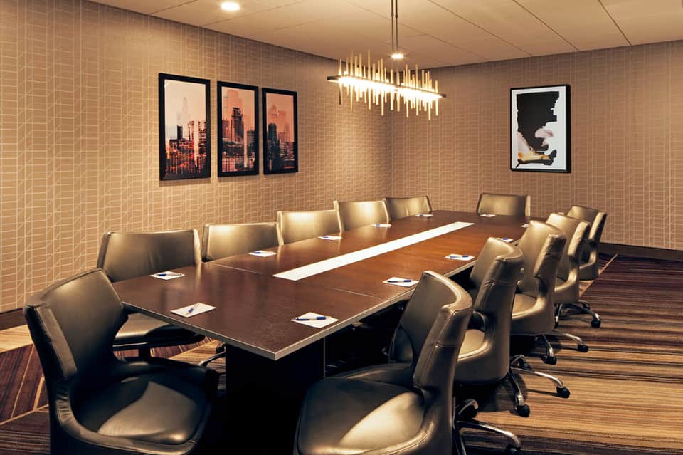 Modern conference room with long wooden table, leather chairs, and city skyline artwork