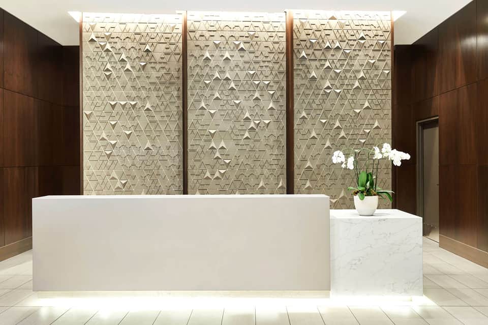 Modern hotel lobby with white marble reception desk and textured wall panels