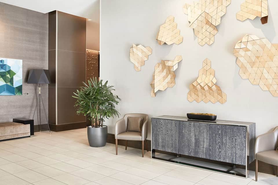Modern hotel lobby with geometric wooden wall art, reception desk, and contemporary furnishings