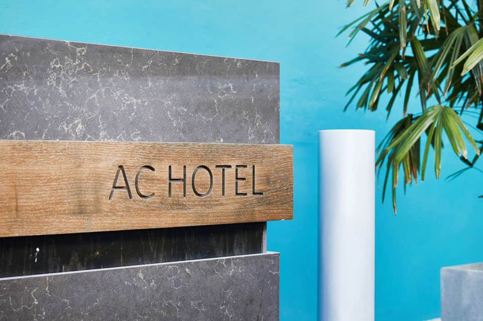 AC Hotel signage with modern architecture and palm fronds against blue sky