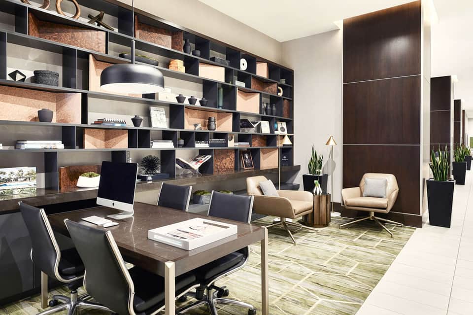 Modern executive office with floor-to-ceiling shelving, dark desk, and comfortable seating area