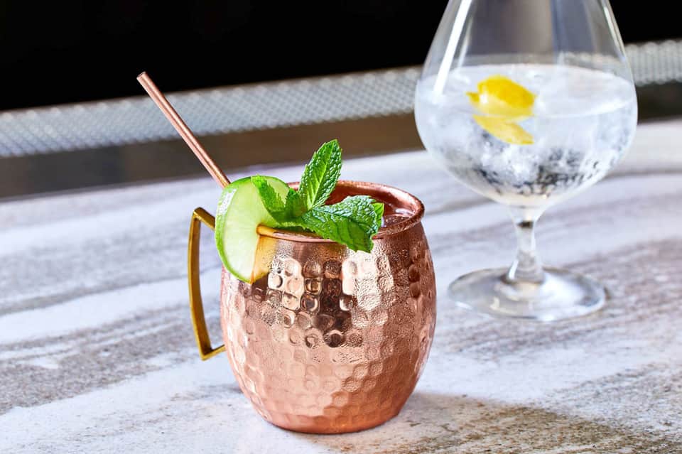 Moscow Mule cocktail in copper mug with lime and mint, poolside setting