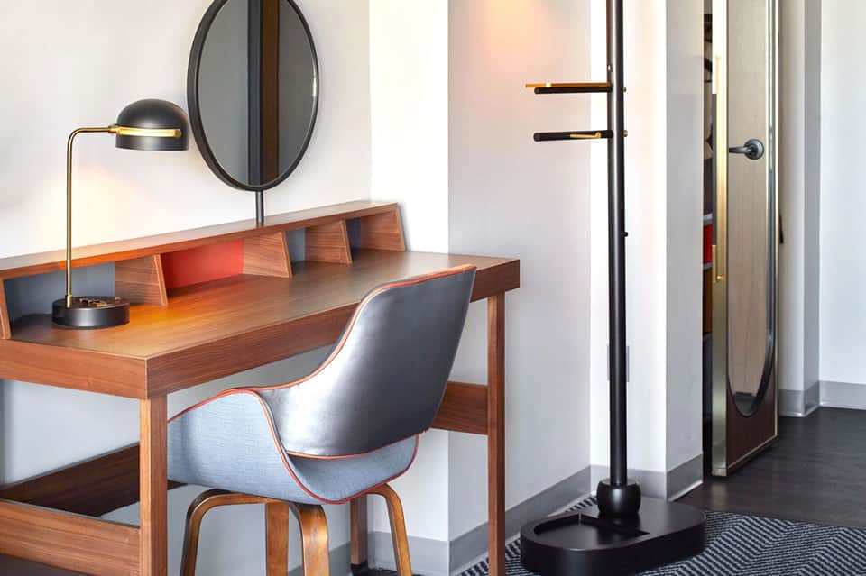 Modern hotel room desk with wooden furniture, round mirror, and minimalist design