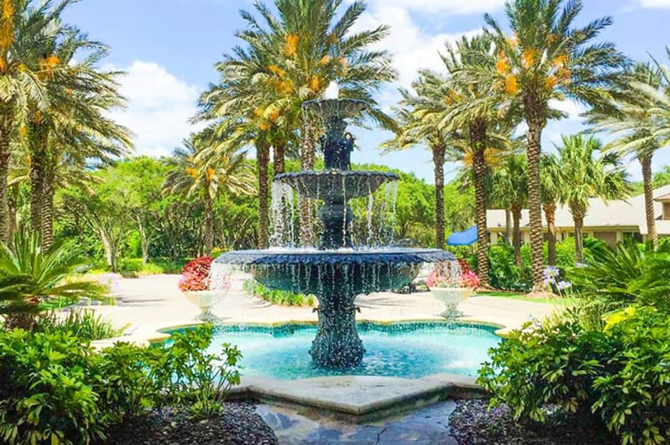 Elegant tiered fountain surrounded by palm trees in tropical resort courtyard with lush greenery