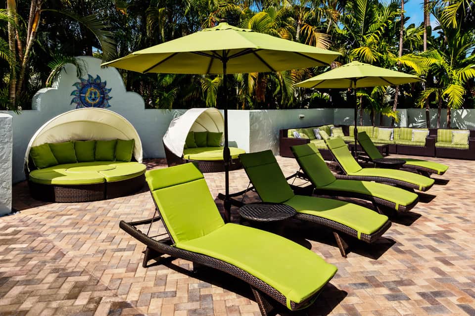 Tropical poolside area with lime green loungers, dome canopies, and lush palm vegetation
