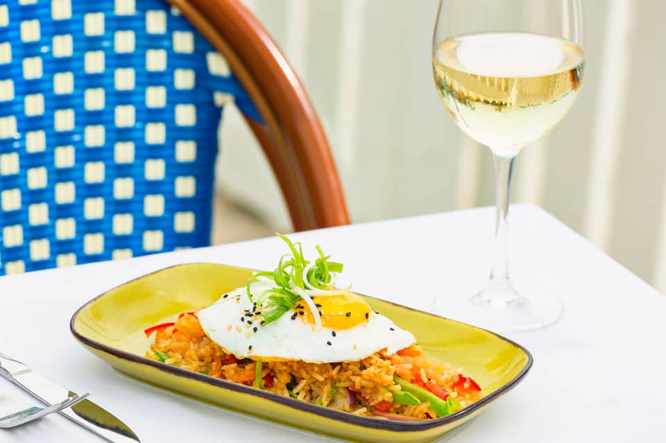 Plated seafood rice dish with poached egg and white wine at upscale restaurant
