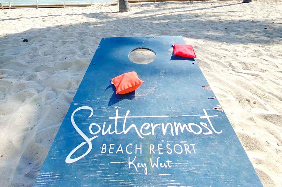 Blue cornhole board branded with Southernmost Beach Resort Key West on sandy beach