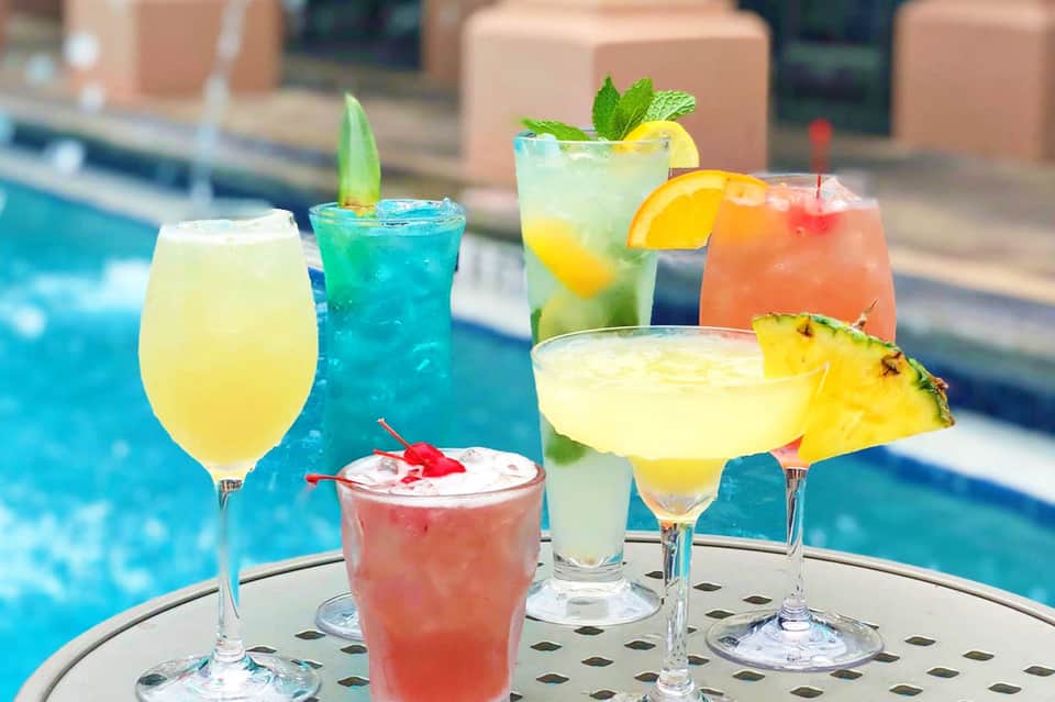 Colorful tropical cocktails with fruit garnishes served poolside at resort bar