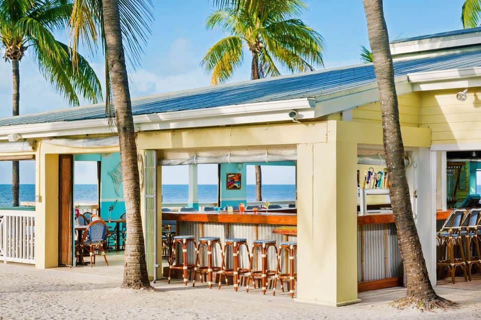 Beachfront pavilion with palm trees, orange chairs, and ocean views