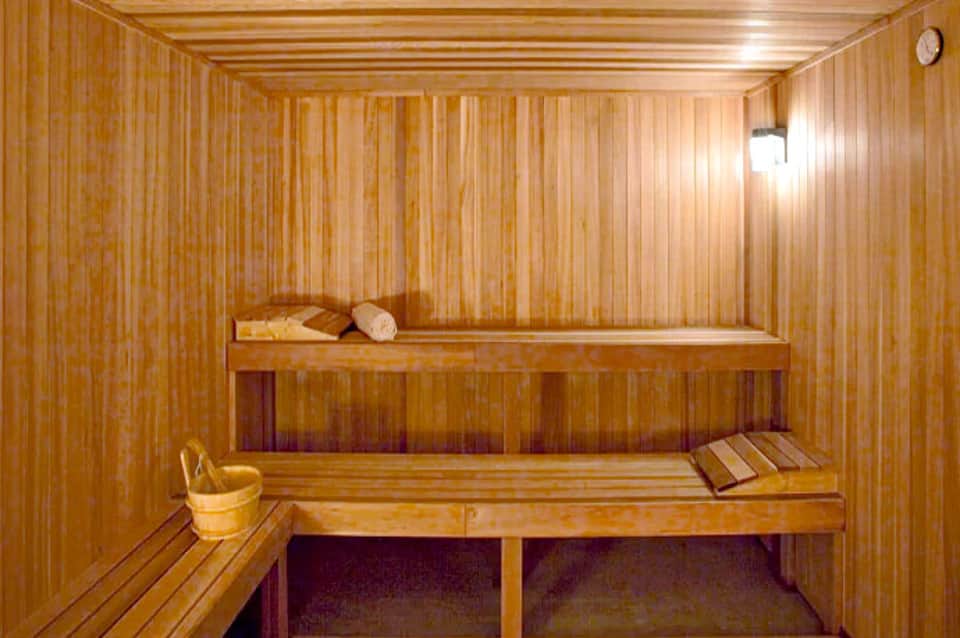 Wooden sauna interior with two-tiered bench seating and traditional sauna accessories