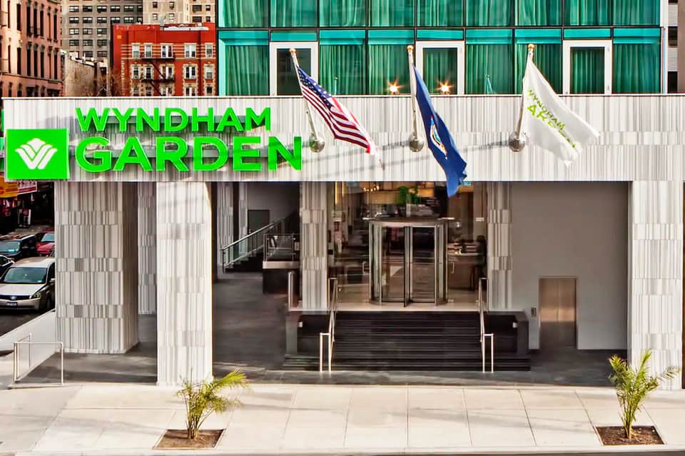 Modern Wyndham Garden hotel entrance with green corrugated metal facade and American flags displayed