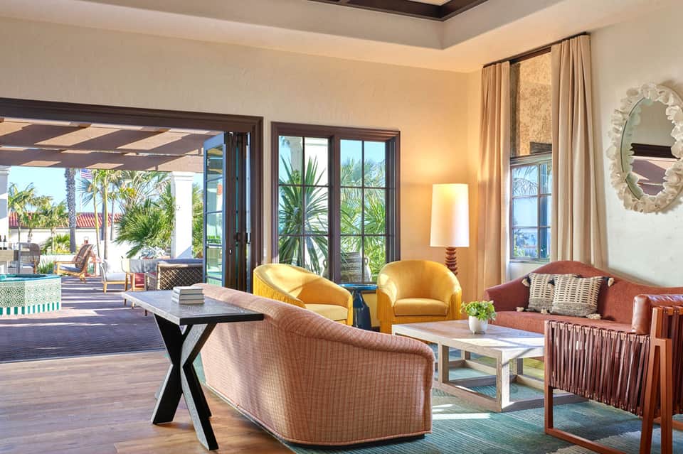 Luxury living room with golden chairs, coral sofa, and ocean view through glass doors