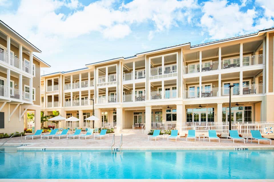 Modern beachfront resort with cream and white multi-story building and turquoise lounge chairs