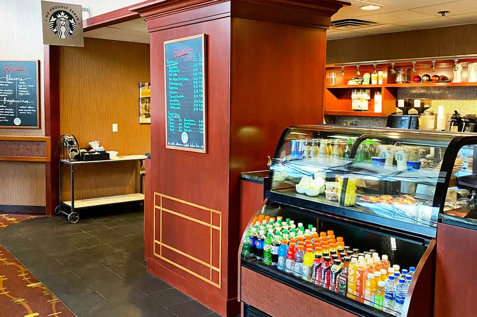 Starbucks café interior with red walls, refrigerated beverage display, and menu boards