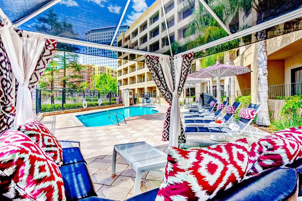 Elegant poolside seating area with geometric patterned cushions and shaded pergola