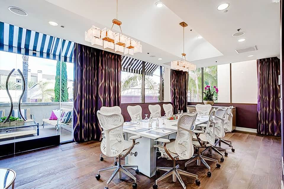 Modern conference room with white ergonomic chairs, striped awnings, and expansive windows with ocean views