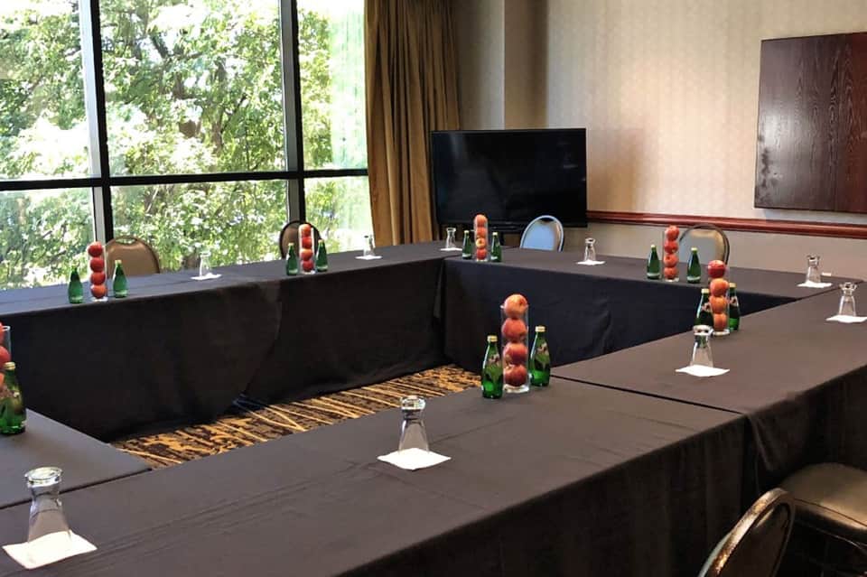 Conference room with U-shaped table setup, decorative fruit centerpieces, and TV screen
