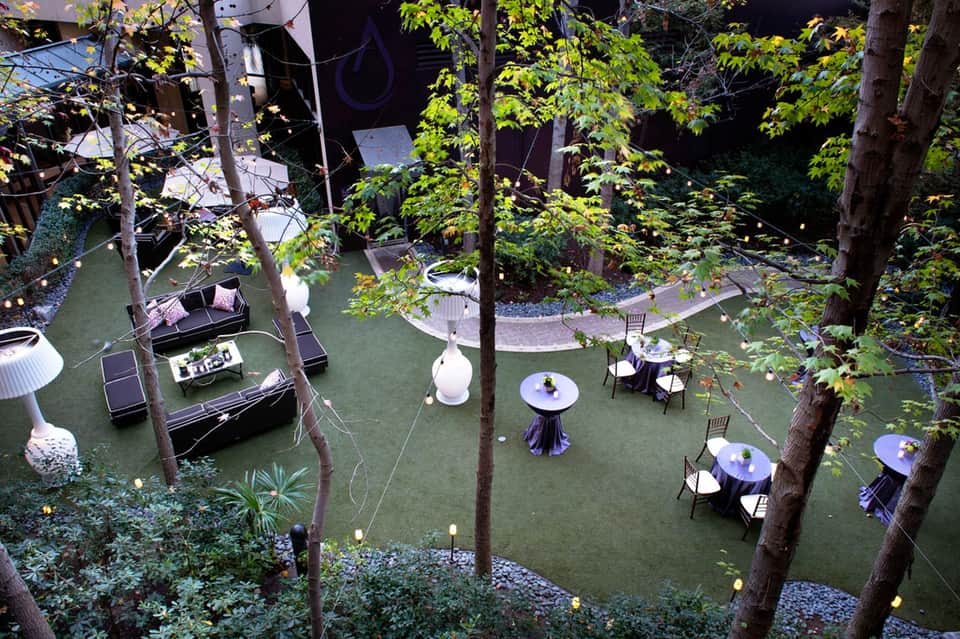 Aerial view of outdoor event space with tables, lighting, and surrounding trees