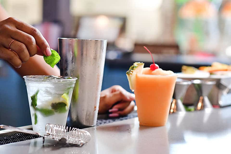 Bartender preparing cocktails with fresh mint and citrus garnishes at a resort bar
