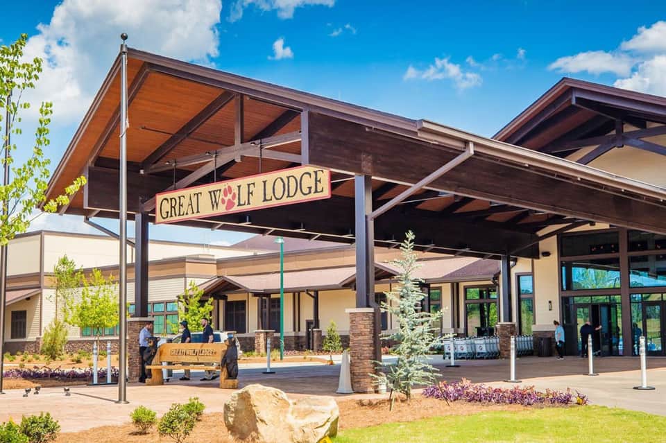 Great Wolf Lodge exterior with wooden architecture, covered pavilion entrance, and landscaped grounds under blue sky