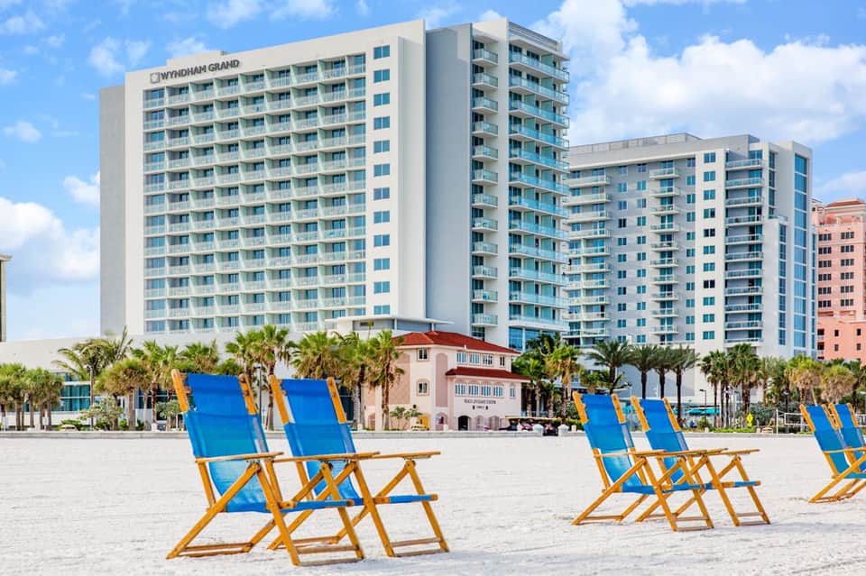 Wyndham Grand beachfront hotel with blue and yellow beach chairs on sandy shore