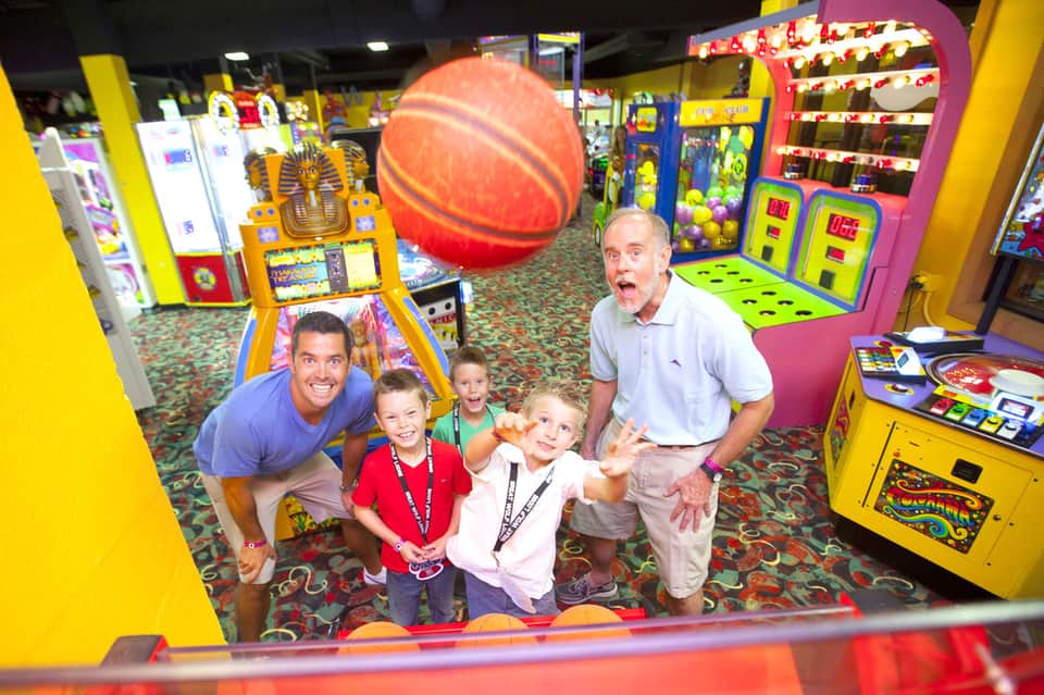 Family playing in colorful arcade with basketball game and ticket redemption machines