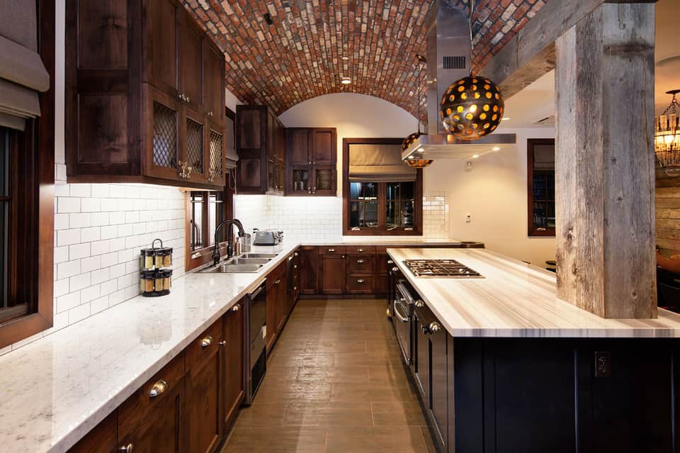 Luxury kitchen with dark wood cabinetry, white subway tile backsplash, marble countertops, and brick barrel ceiling