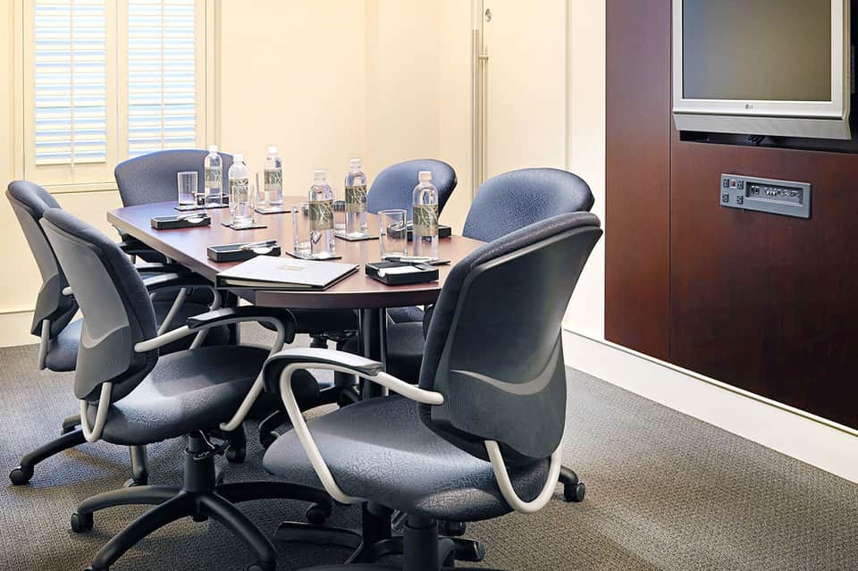 Professional conference room with oval table, ergonomic chairs, water bottles, and modern office setup