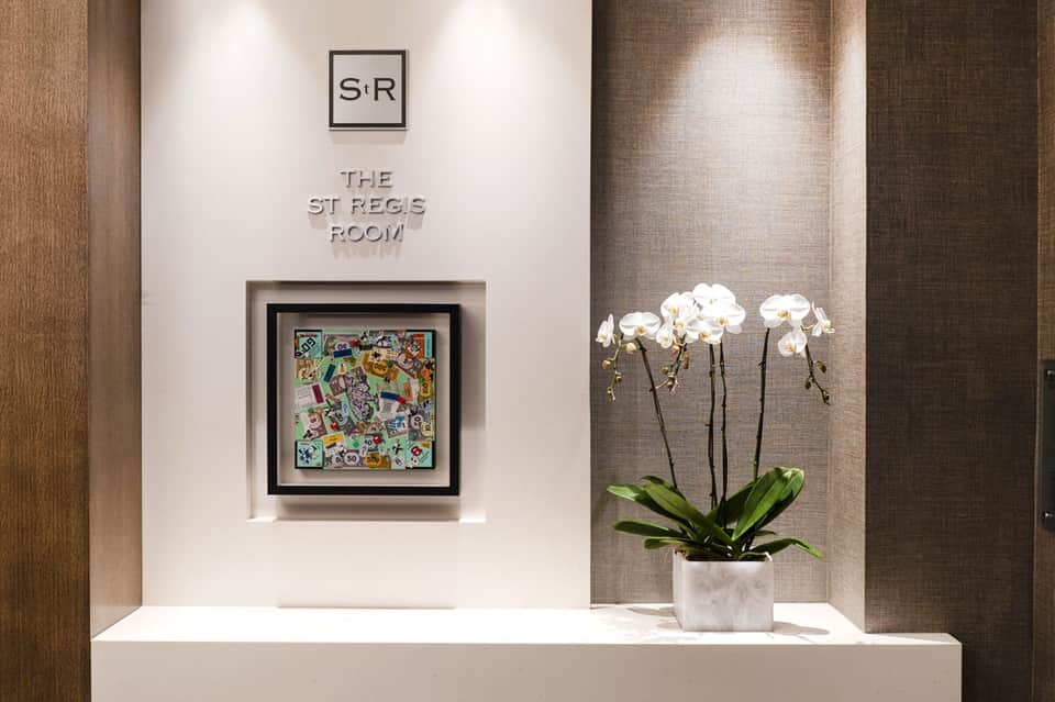 Elegant hallway entrance to St Regs Room with white orchids and modern wall art