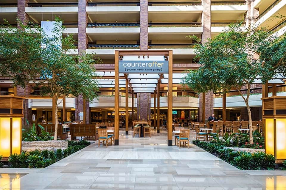Indoor shopping mall with wooden beams, lush greenery, and Counteroffer storefront signage