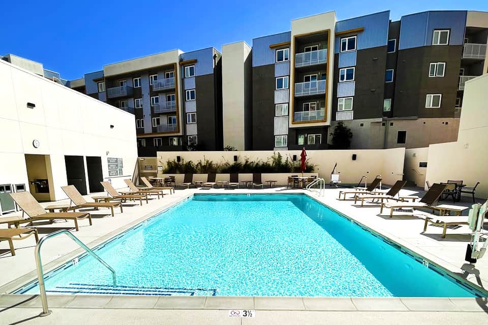 Resort pool with turquoise water, lounge chairs, and modern apartment buildings