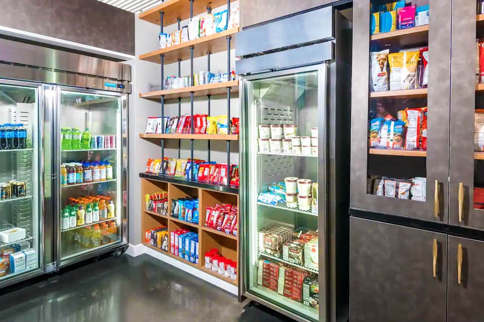 Modern convenience store with refrigerated beverage cases, glass-door freezers, and stocked shelving units displaying groceries and snacks.