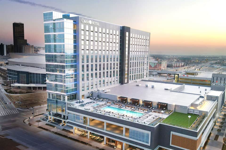 Omni Hotel high-rise building at dusk with rooftop pool and lounge area overlooking urban waterfront