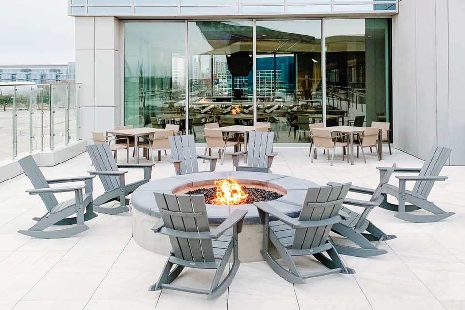 Rooftop terrace with fire pit, Adirondack chairs, and glass doors to indoor seating area
