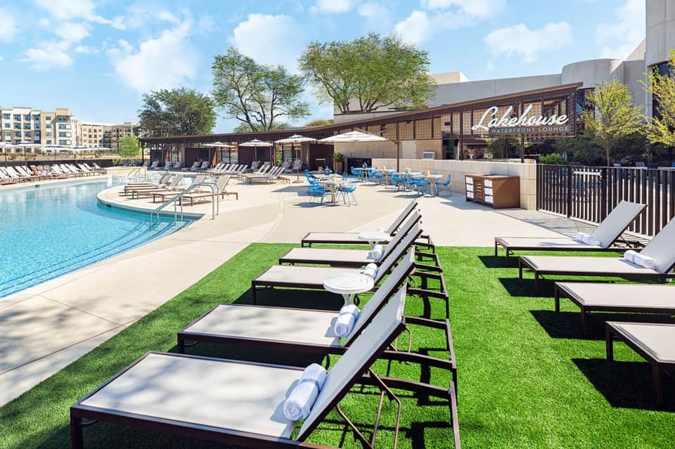 Lakehouse Waterfront Lounge pool area with lounge chairs, lawn seating, and waterside building