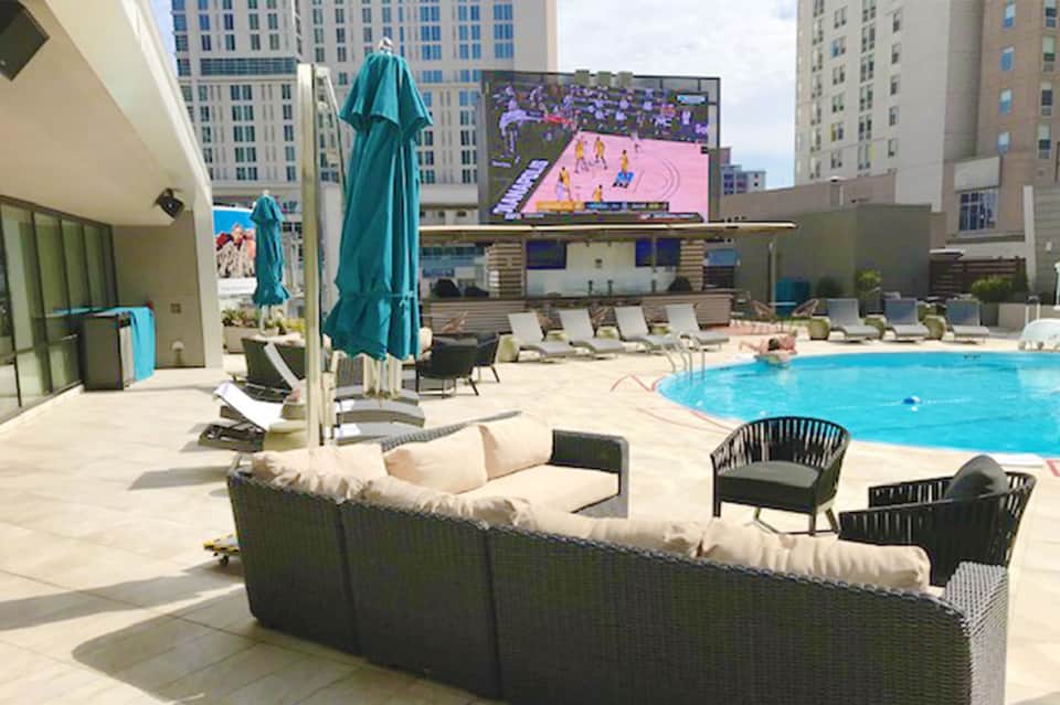 Urban rooftop pool with loungers, umbrellas, and city skyline views