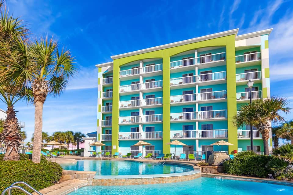 Colorful lime-green and turquoise multi-story beachfront hotel with swimming pools