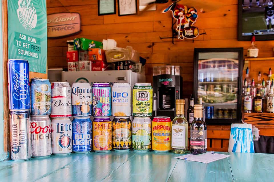 Bar counter displaying various beer and beverage cans in a casual wooden establishment