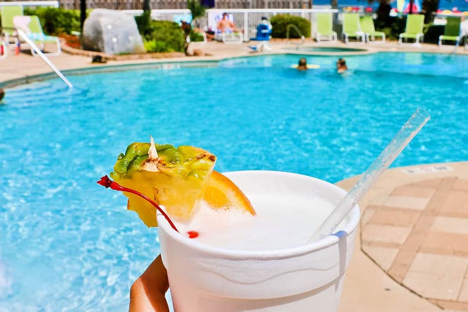 Tropical cocktail with pineapple garnish by poolside during daytime at resort