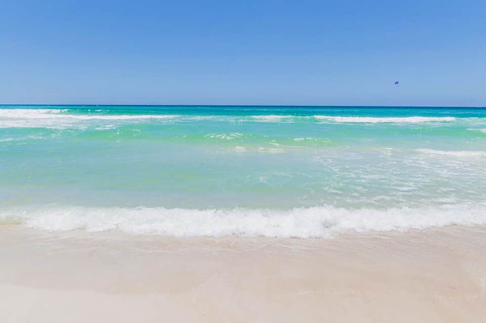 Pristine turquoise ocean with white sand beach and gentle waves under clear blue sky